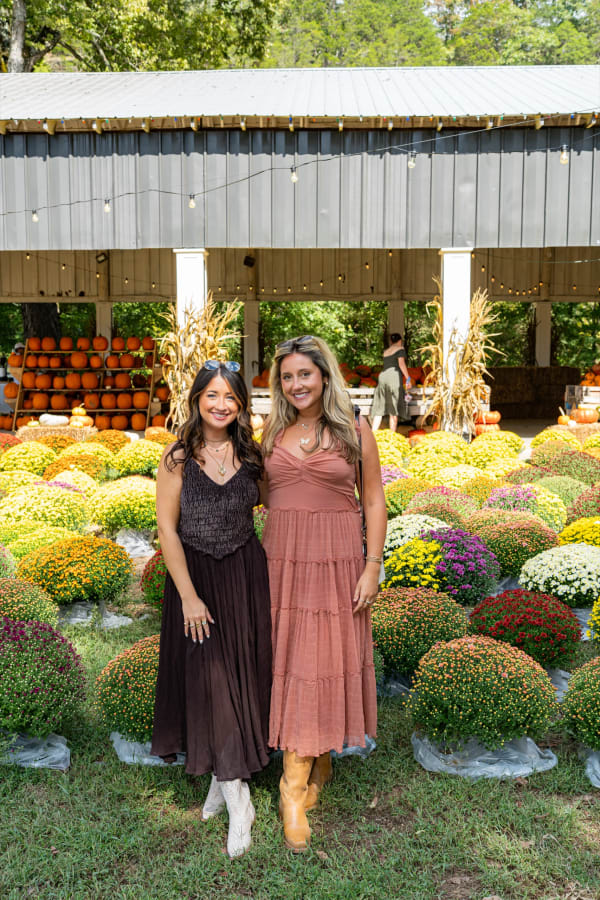 Friends posing in front of the mums at the pavilion