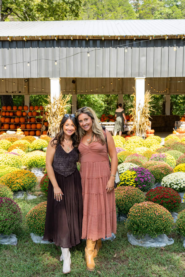 Friends posing in front of the mums at the pavilion
