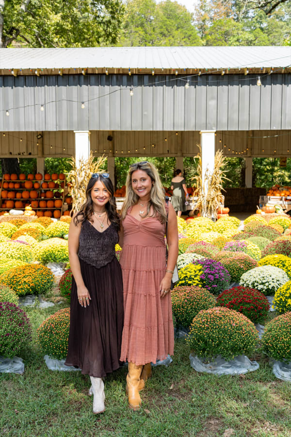 Friends posing in front of the mums at the pavilion