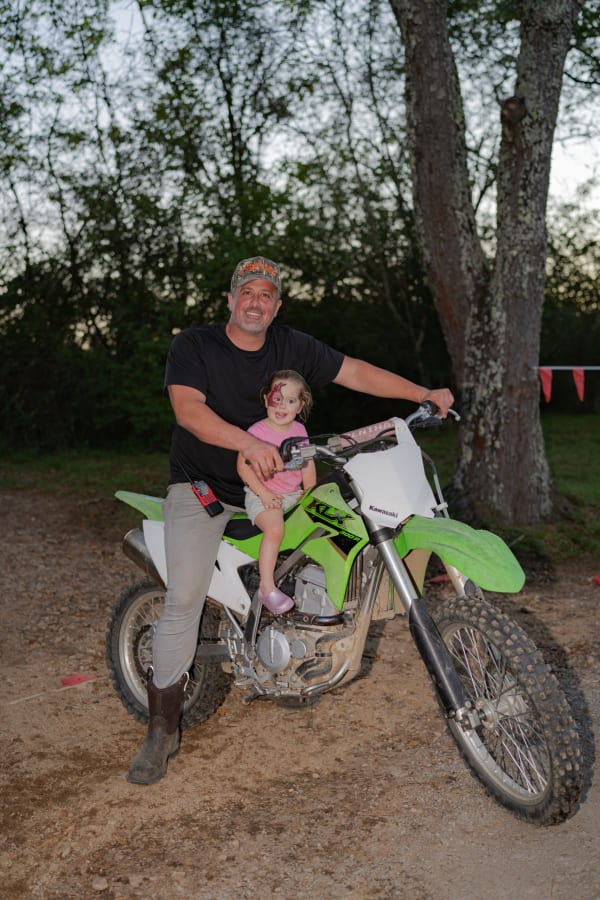 Dad and daughter on a green dirt bike