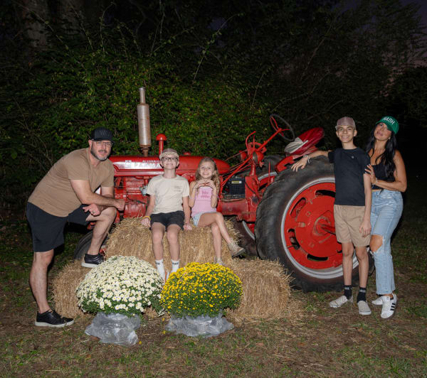 Family posing with a vintage red tractor at night