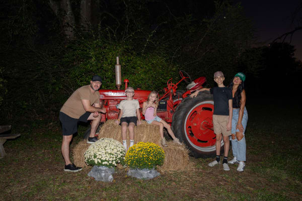Family posing with a vintage red tractor at night