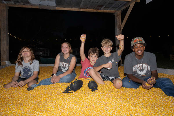 Kids throwing corn in the corn pit at night