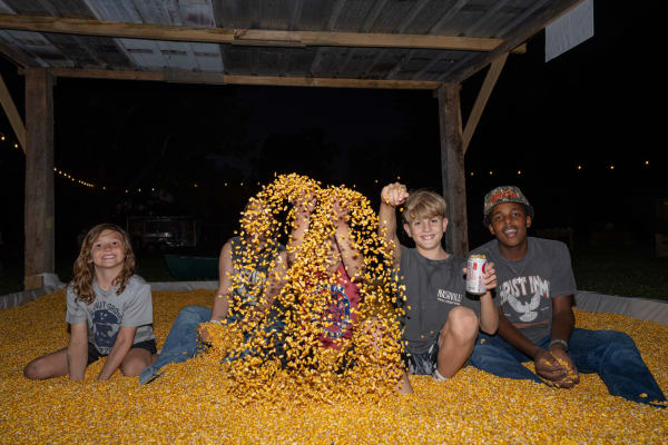 Kids throwing corn in the corn pit at night