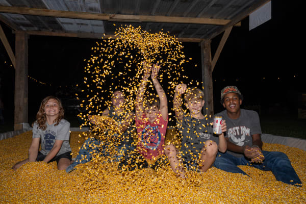 Kids throwing corn in the corn pit at night