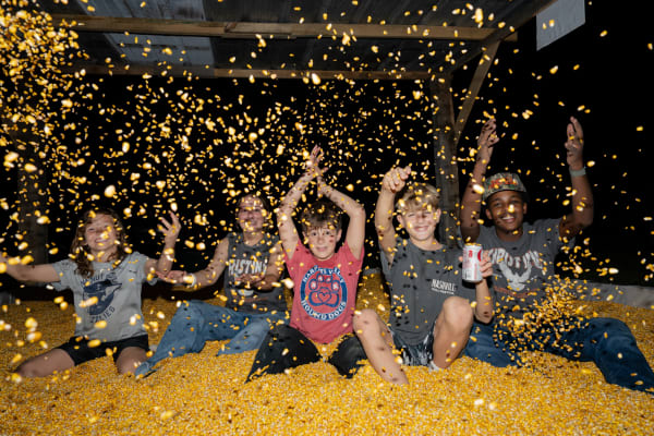 Kids throwing corn in the corn pit at night