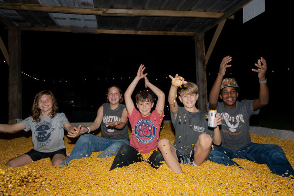Kids throwing corn in the corn pit at night