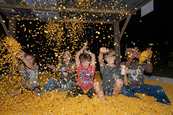 Kids throwing corn in the corn pit at night