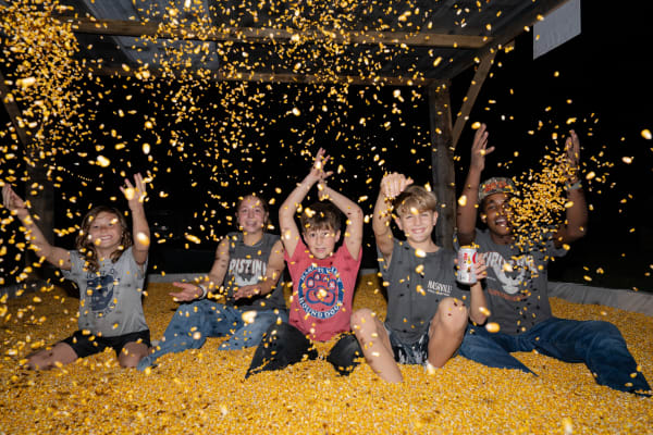 Kids throwing corn in the corn pit at night