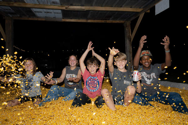 Kids throwing corn in the corn pit at night