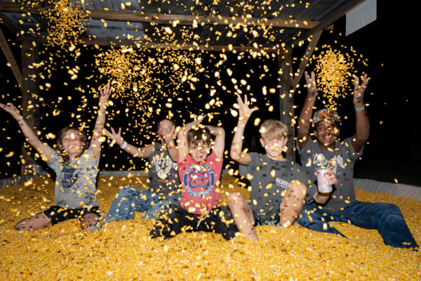 Kids throwing corn in the corn pit at night