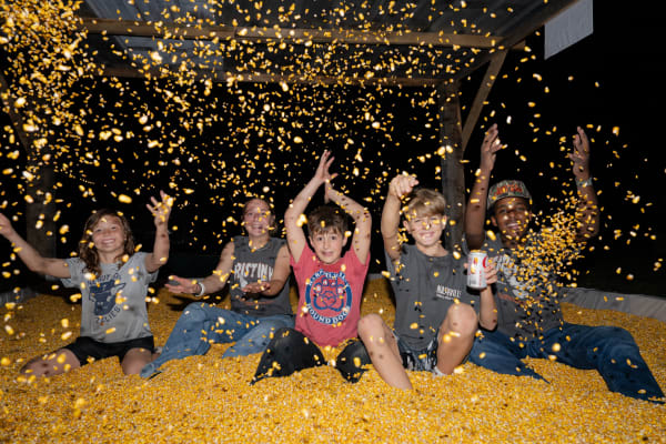 Kids throwing corn in the corn pit at night