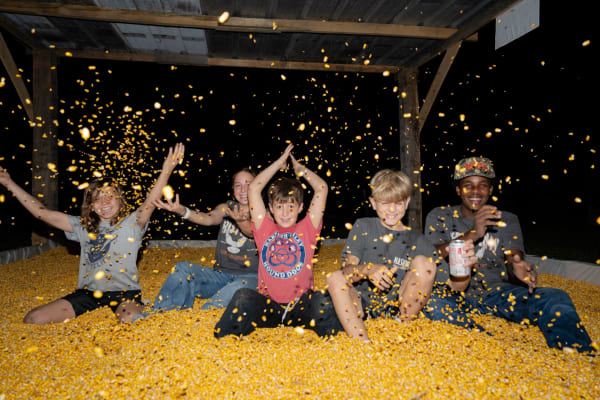 Kids throwing corn in the corn pit at night