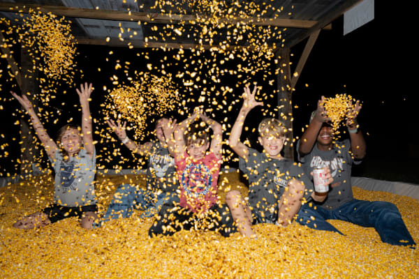 Kids throwing corn in the corn pit at night
