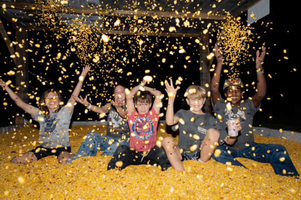 Kids throwing corn in the corn pit at night