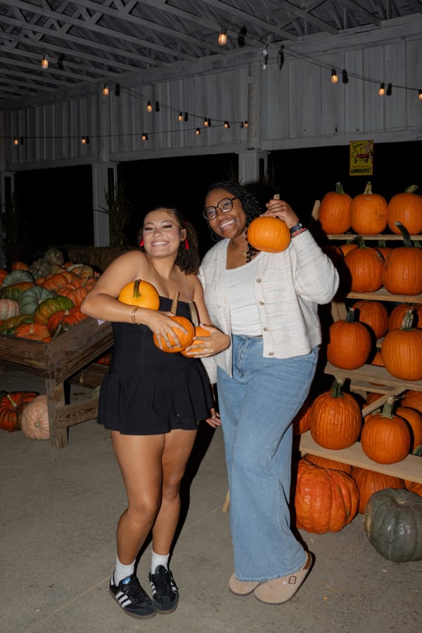 Friends holding pumpkins inside the pumpkin barn