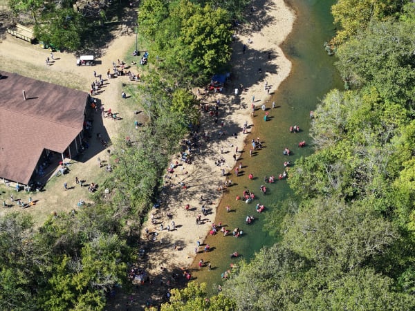 Aerial view of guests along the river beside the barn