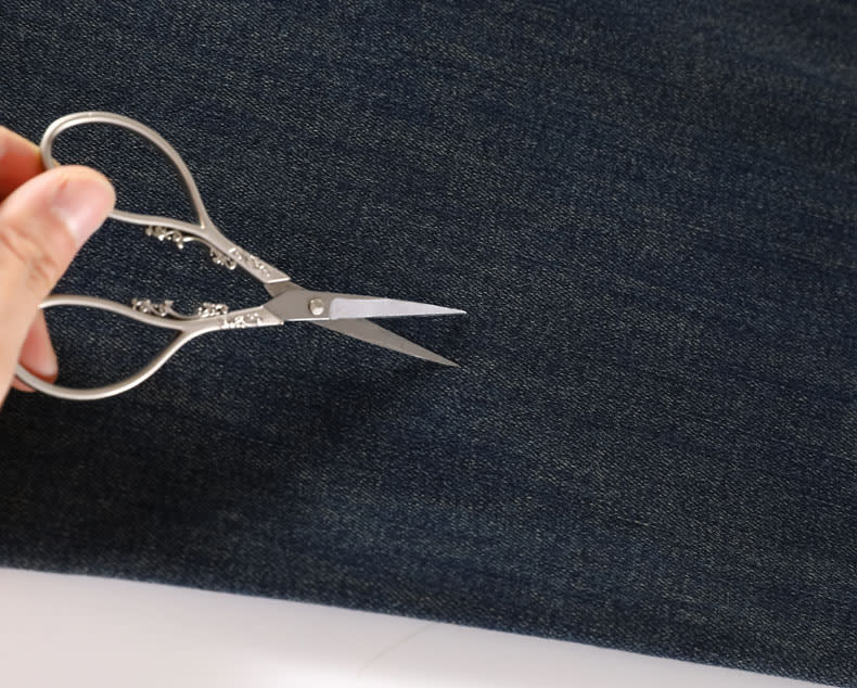 YEEYEEWang wide-leg jeans, Asian-fit cut, close-up of dense twill denim texture with scissors placed on the fabric.