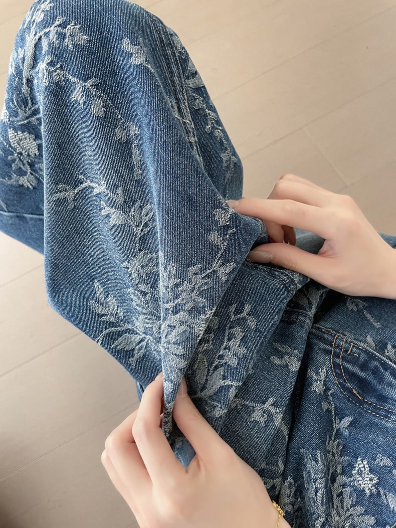 YEEYEEWang jupe longue en denim, coupe Asian-fit, gros plan sur les mains soulevant le tissu jacquard floral en relief.