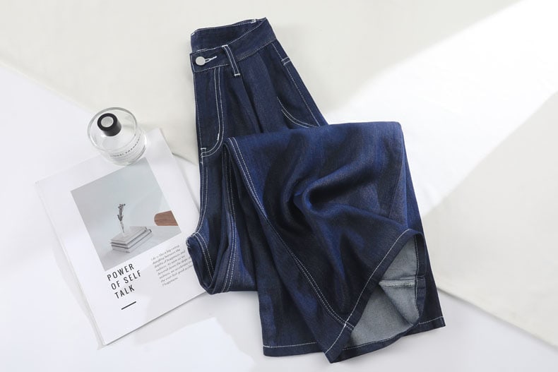 YEEYEEWang Wide-Leg Jeans in Denim Blue, Asian-fit cut, angled flat lay with one leg folded to show fluid drape and side seam lines.