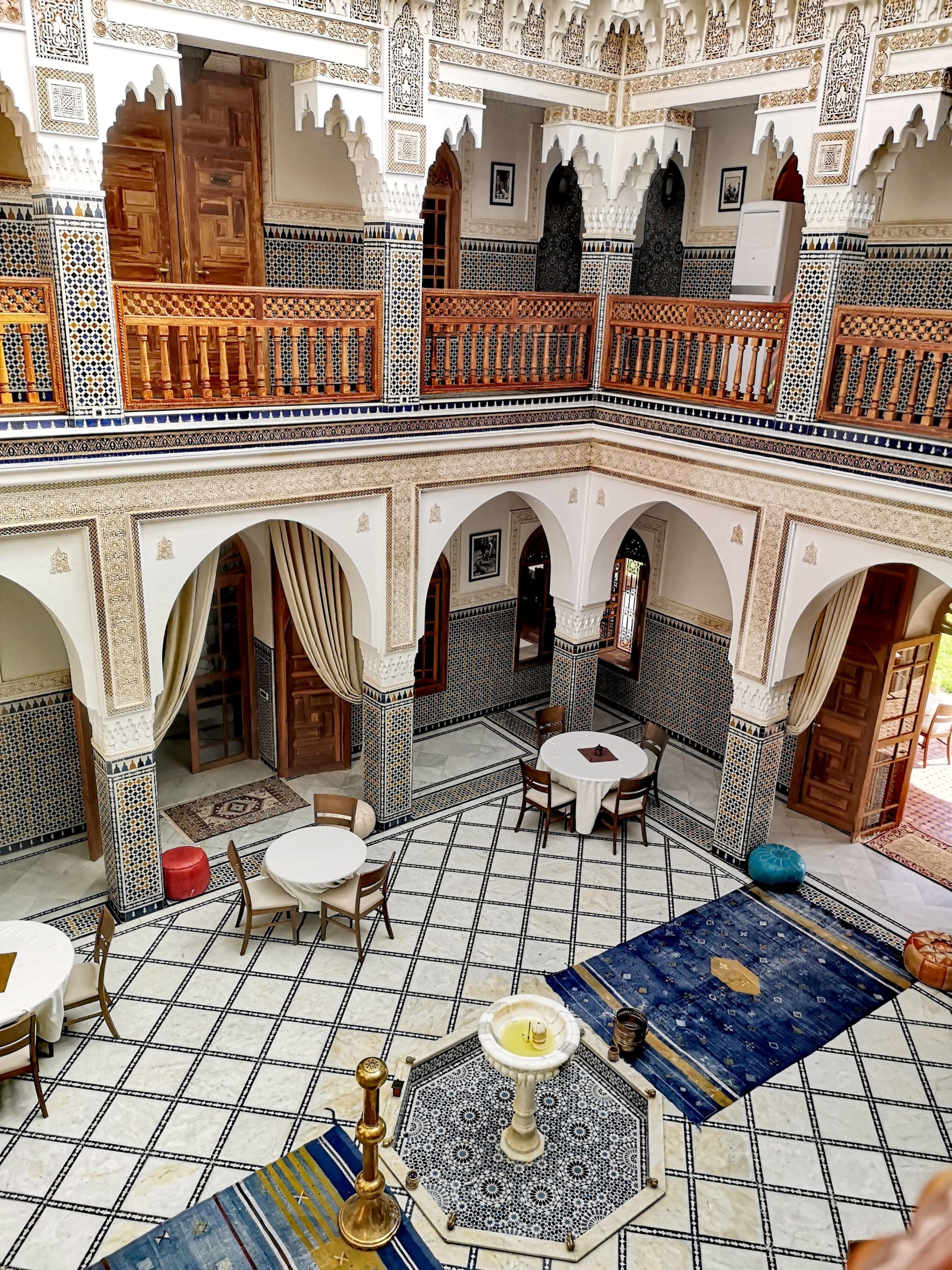 Le patio central du Riad La Petite Maison à Fès, sol en zellige et hautes portes sculptées