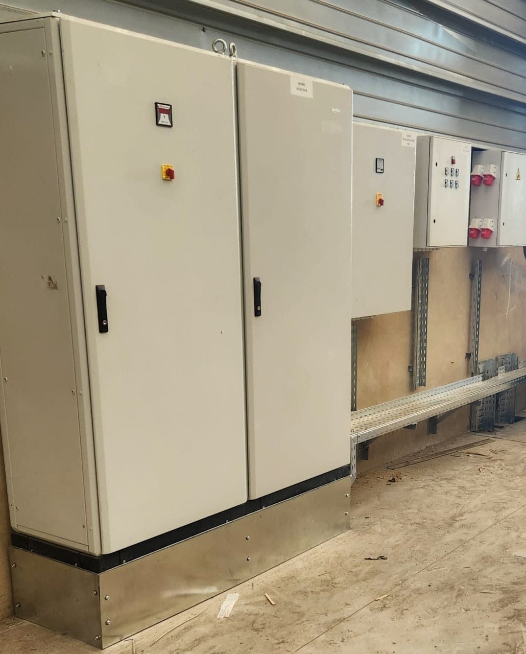 Armoires électriques sur socle inox et coffrets de prises industrielles raccordés par chemin de câbles