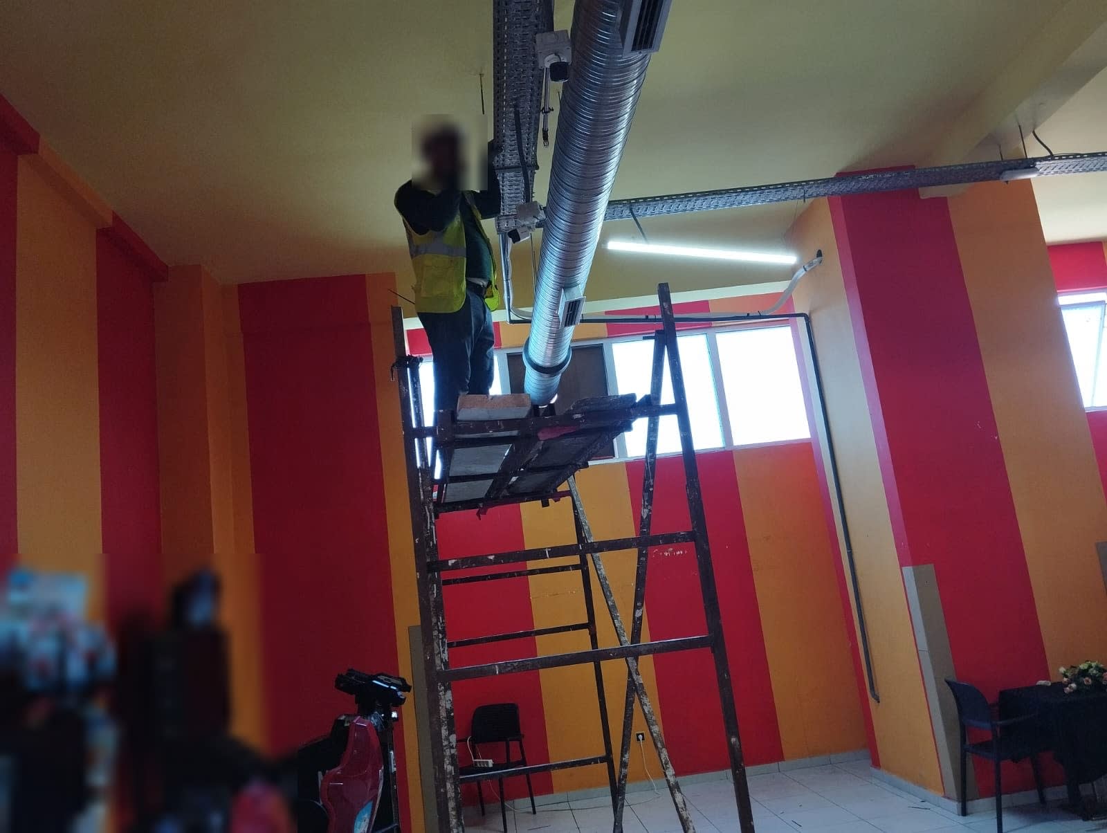 Pose d’une gaine de ventilation spiralée et d’un chemin de câbles depuis un échafaudage roulant