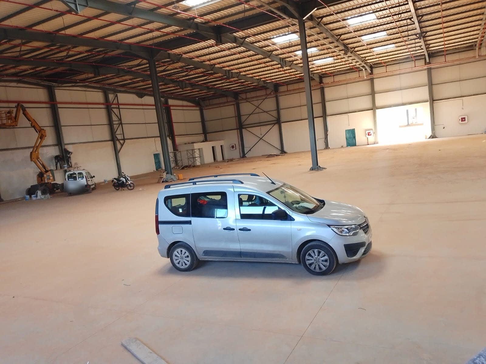 Grand hall industriel neuf à charpente métallique avec véhicule d’intervention et nacelle