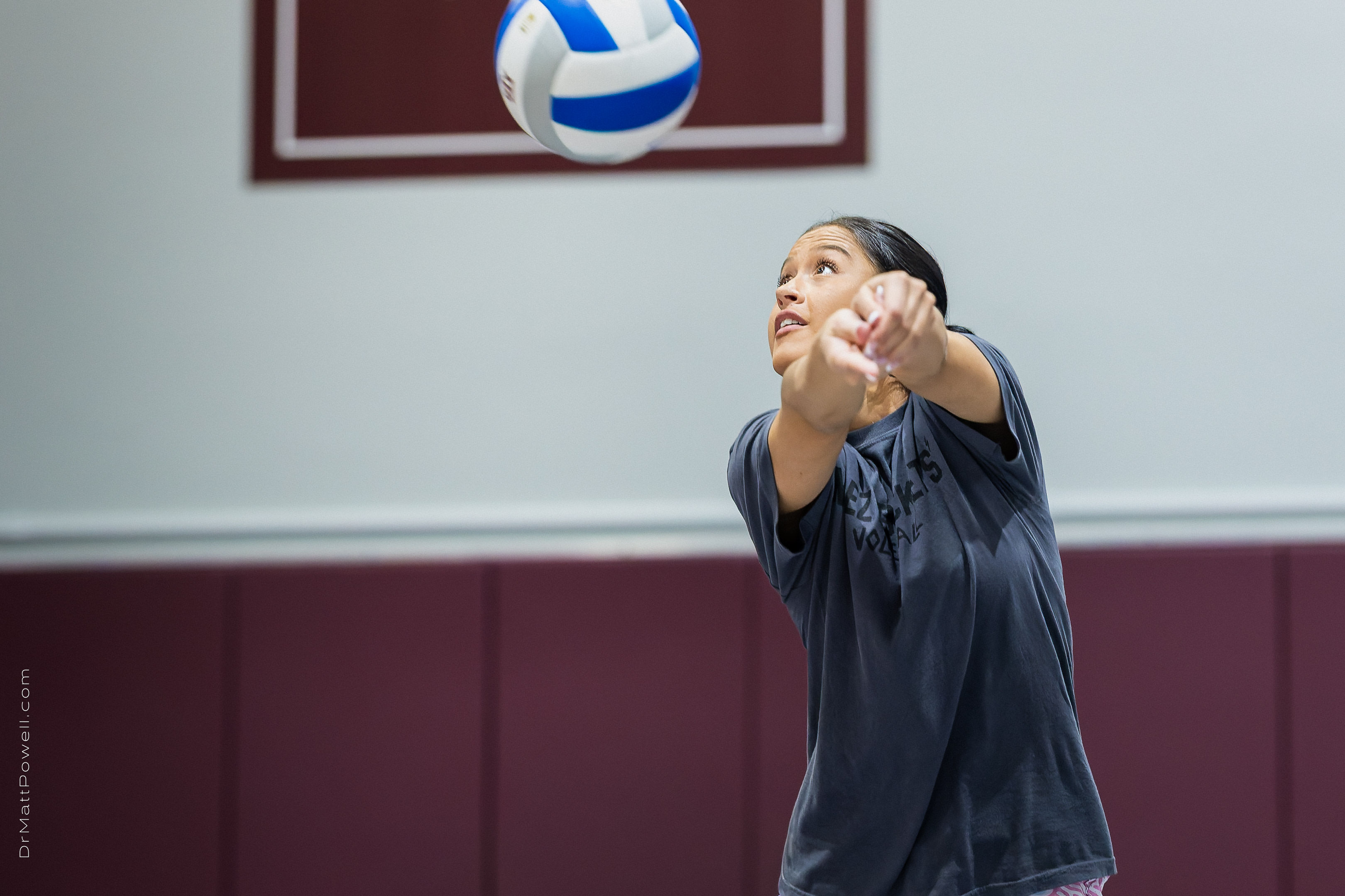 Gabi Rodriguez tracks a blue-and-white volleyball above her outstretched arms during the clinic.