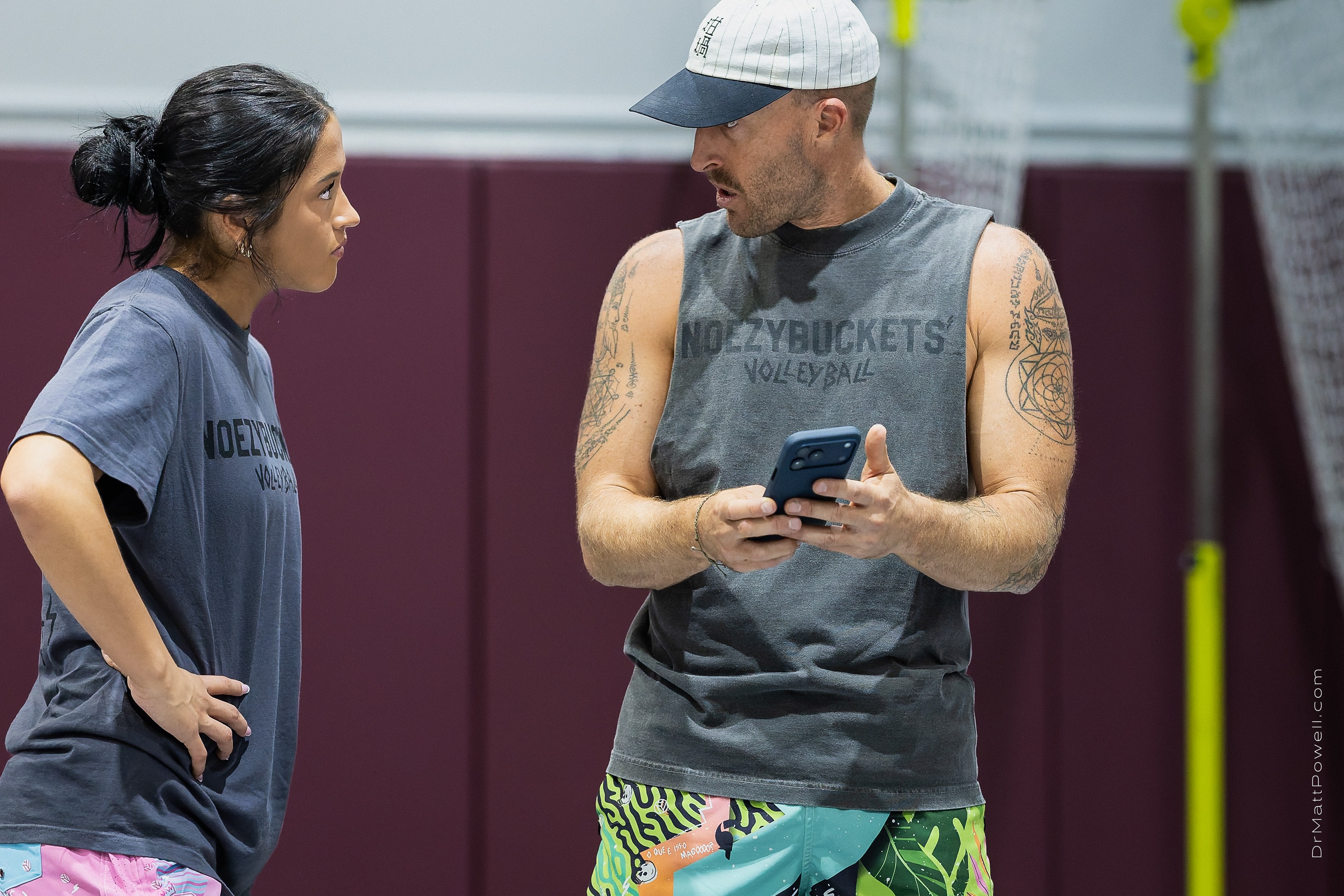 Dustin Watten speaks with Gabi Rodriguez while holding a phone during their volleyball clinic.