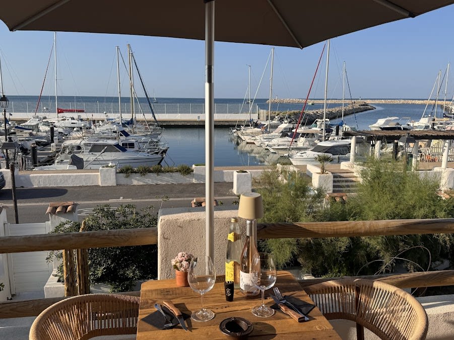 Table dressée sur la terrasse avec vue sur le port et la Méditerranée