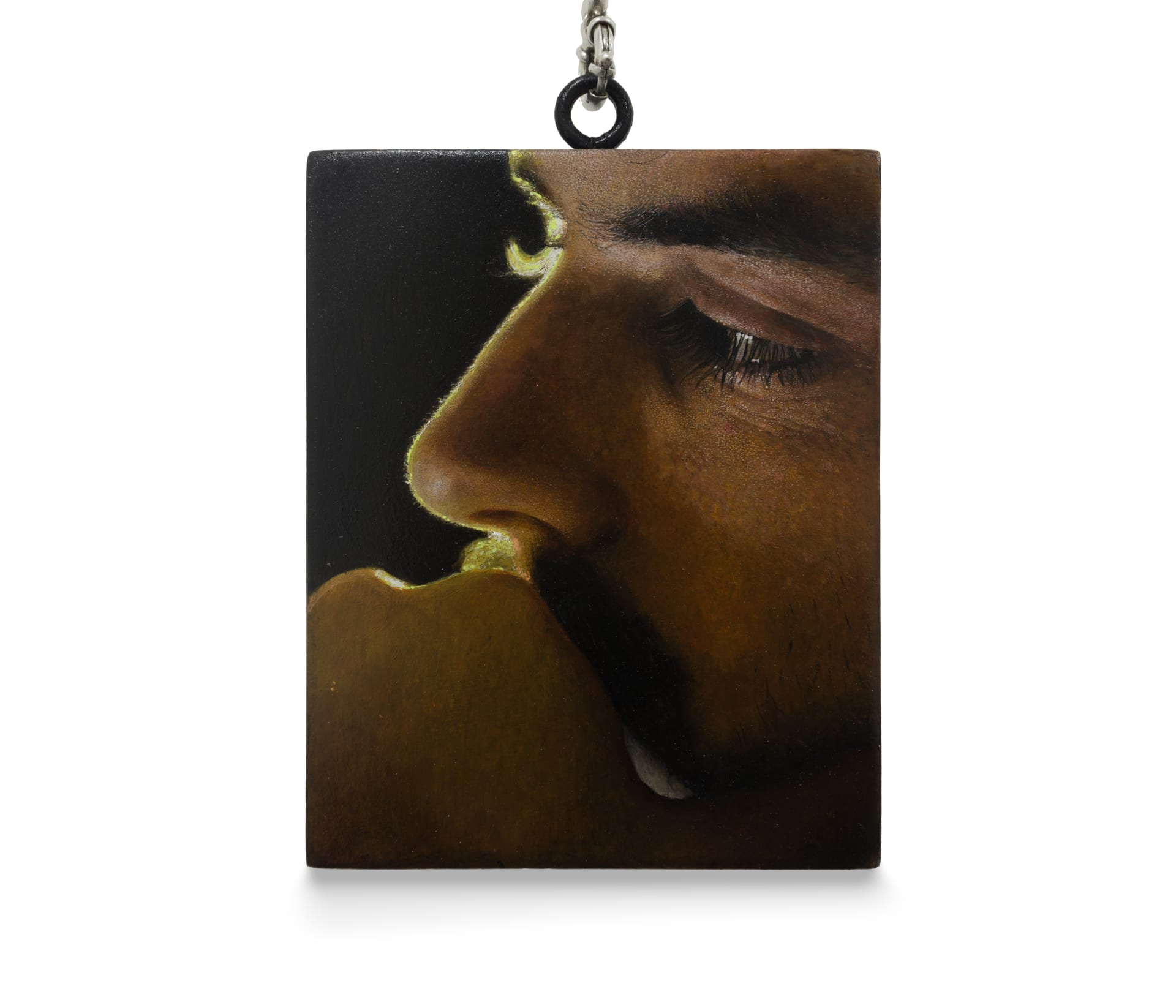 a painting by Ki Yoong of a close up of a male face against a dark background which hangs from a silver necklace