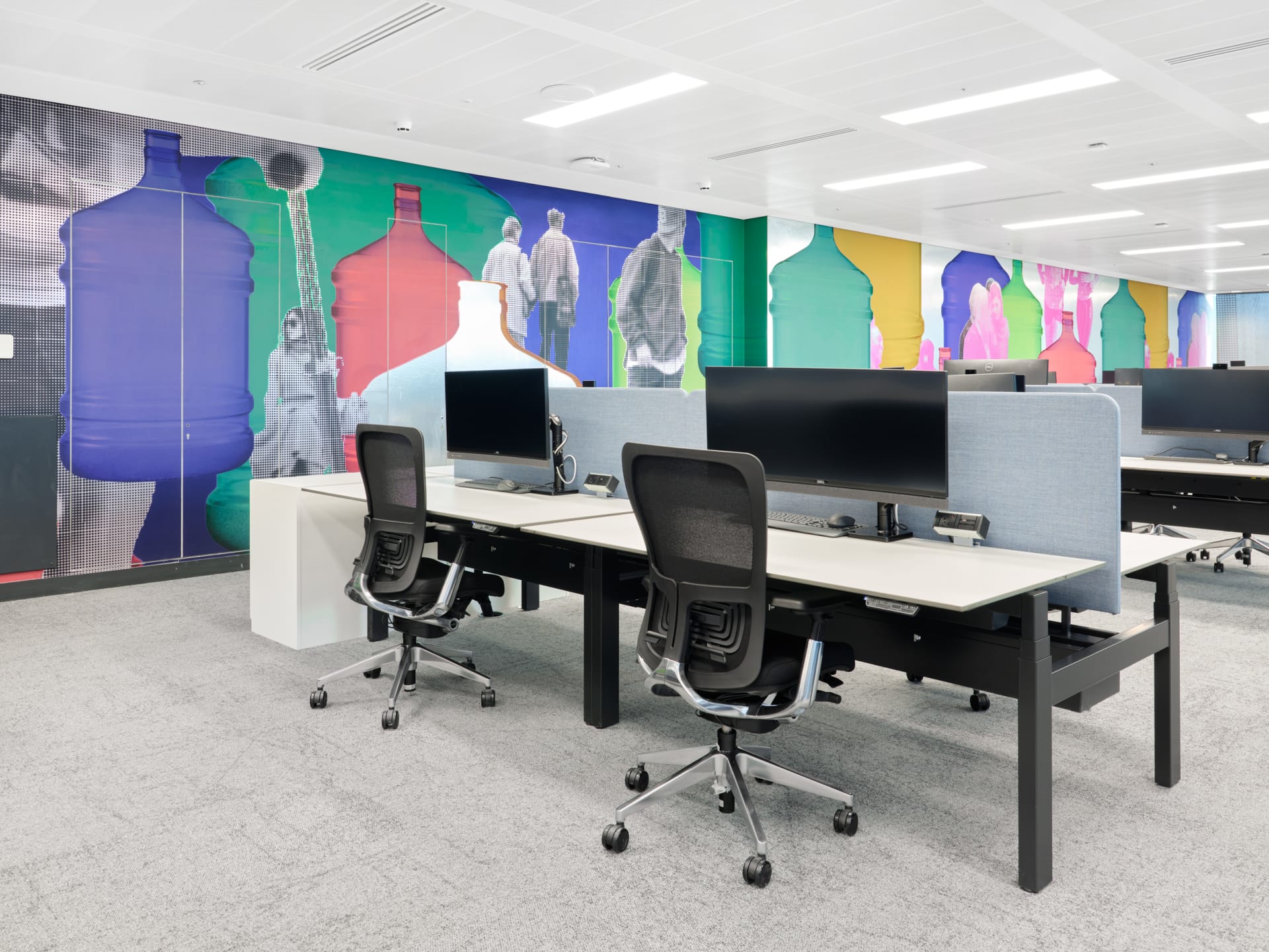 An installation by Simeon Barclay in an office composed of bright collaged people standing and walking