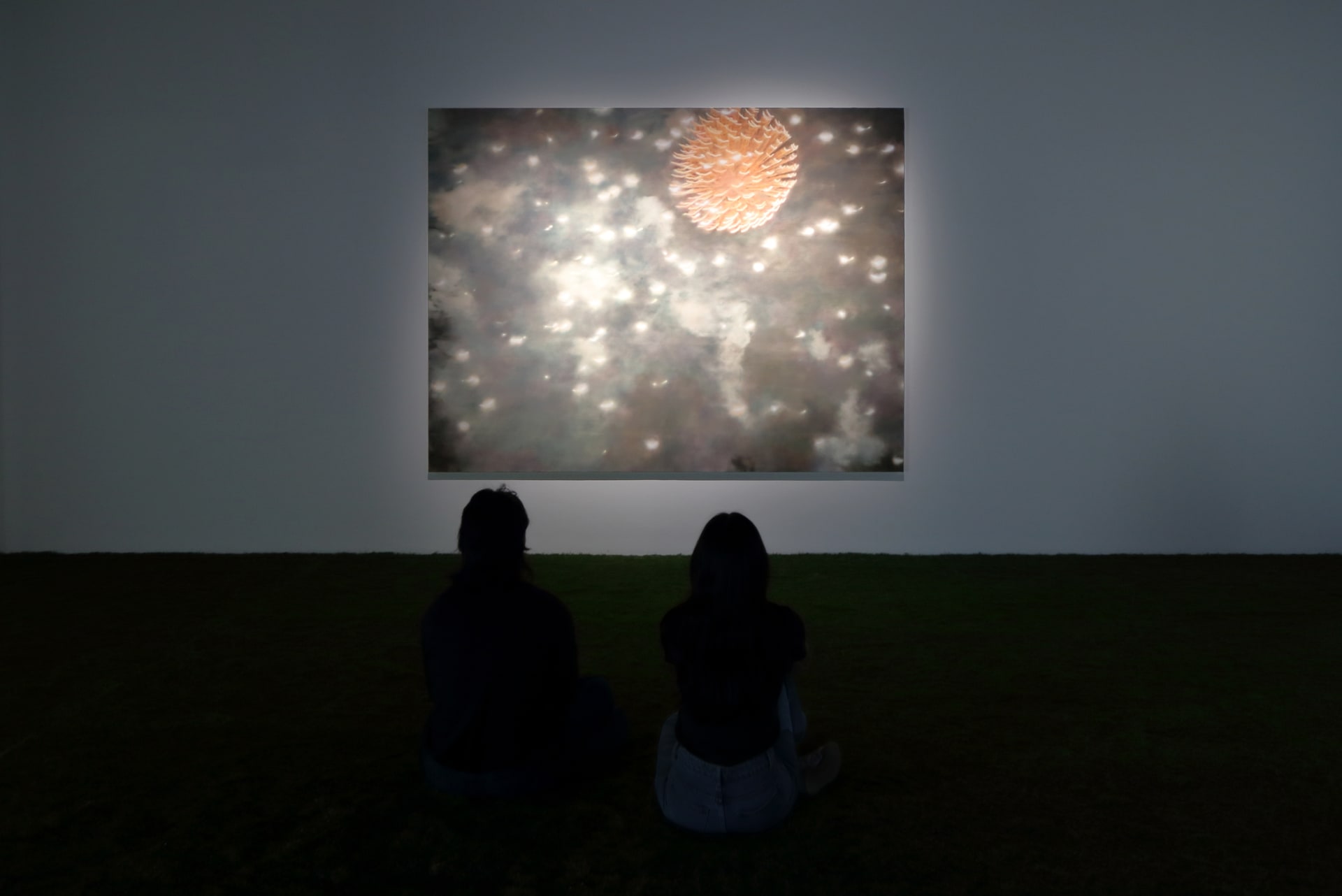 Installation view of a dark room with a painting by James Prapaithong softly spotlit