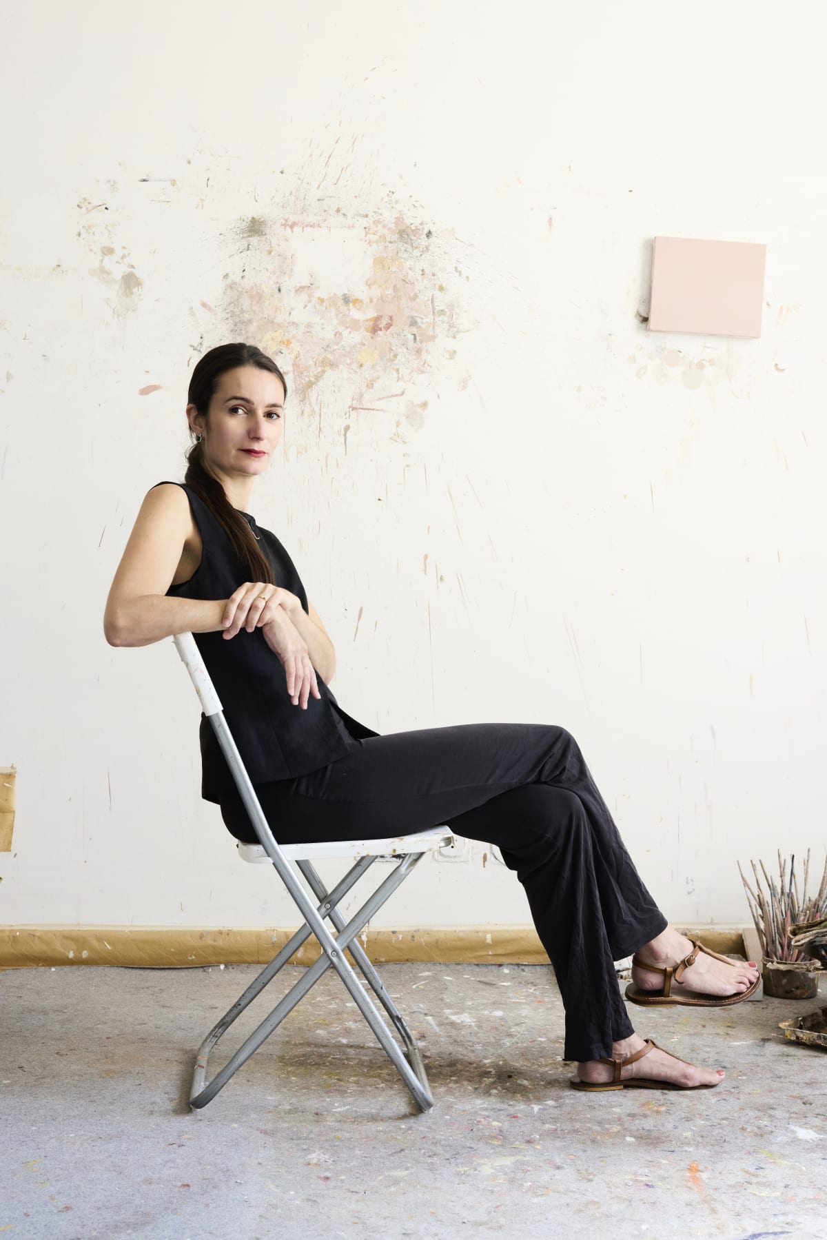 A portrait of Marta Ravasi sat on a chair in her studio