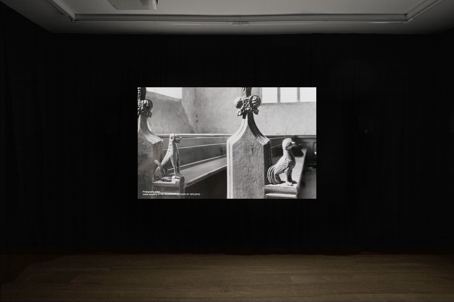 An installation image of Elizabeth Price's film in Workplace's gallery in Margaret Street - a black and white close up of pews in a chuch