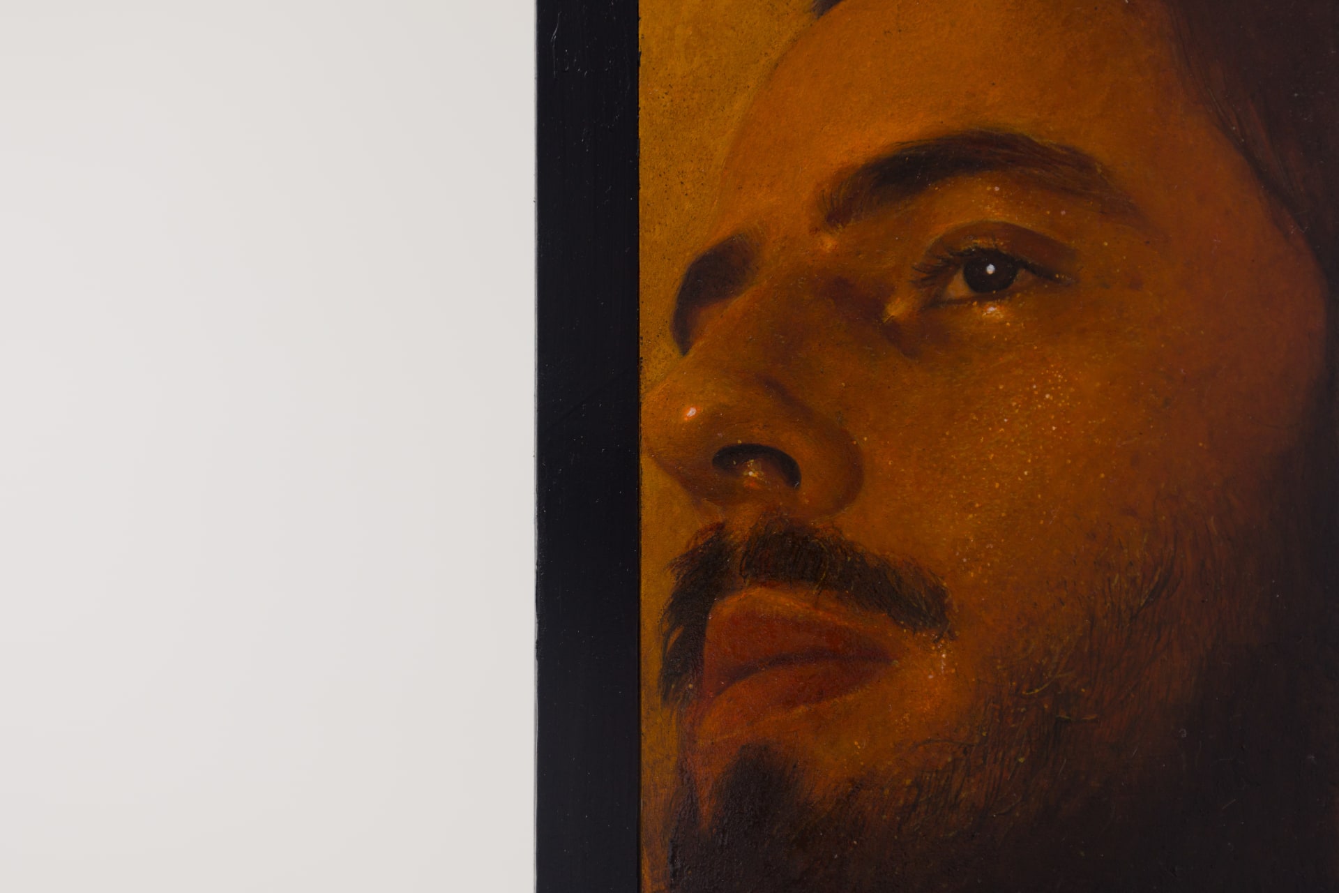 A painting by Ki Yoong of a softly lit young man's face with steel brackets attached to the top and bottom