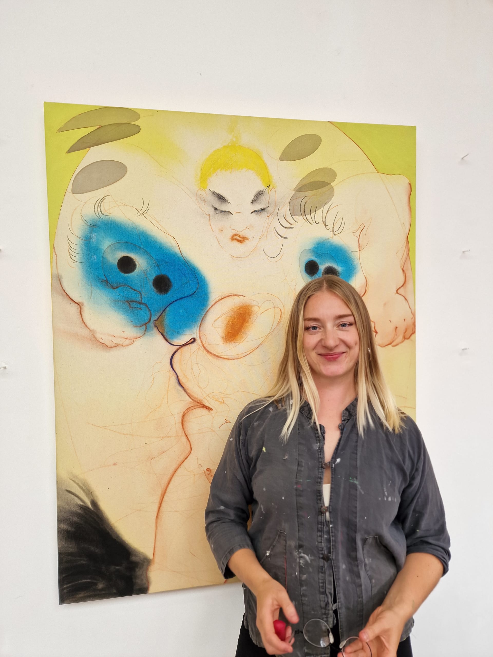 A portrait of Zoe Spowage in front of one of her paintings