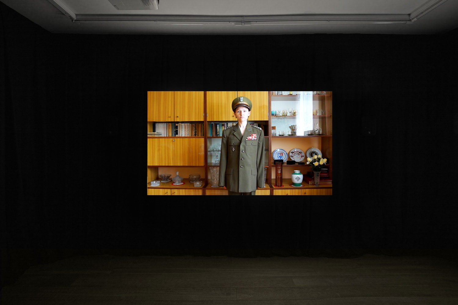 An installation image of Agnieszka Szczotka's film in Workplace's gallery in Margaret Street - Agnieszka wearing her grandfather's military uniform in the living room of her grandparents