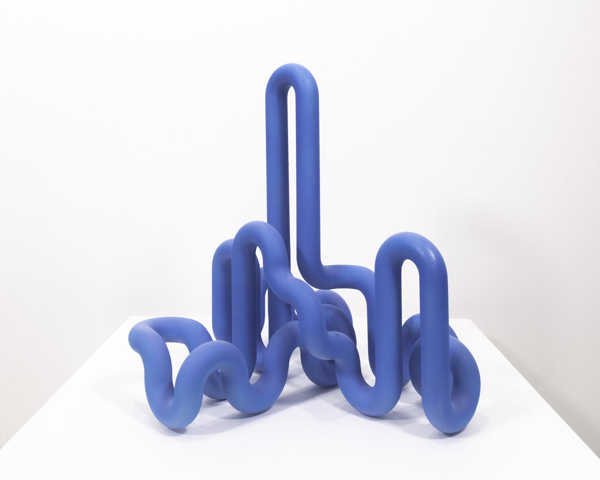A bright blue sculptural artwork by Jacob Dahlgren made of PLA plastic that resembles a looping pipe
