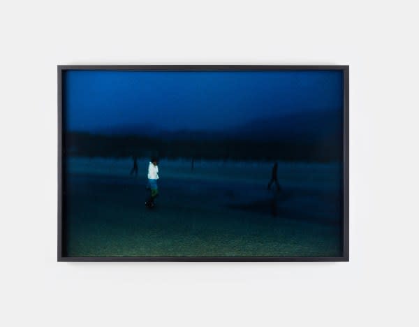 A photo by Nan Goldin of a figure standing on a dark beach