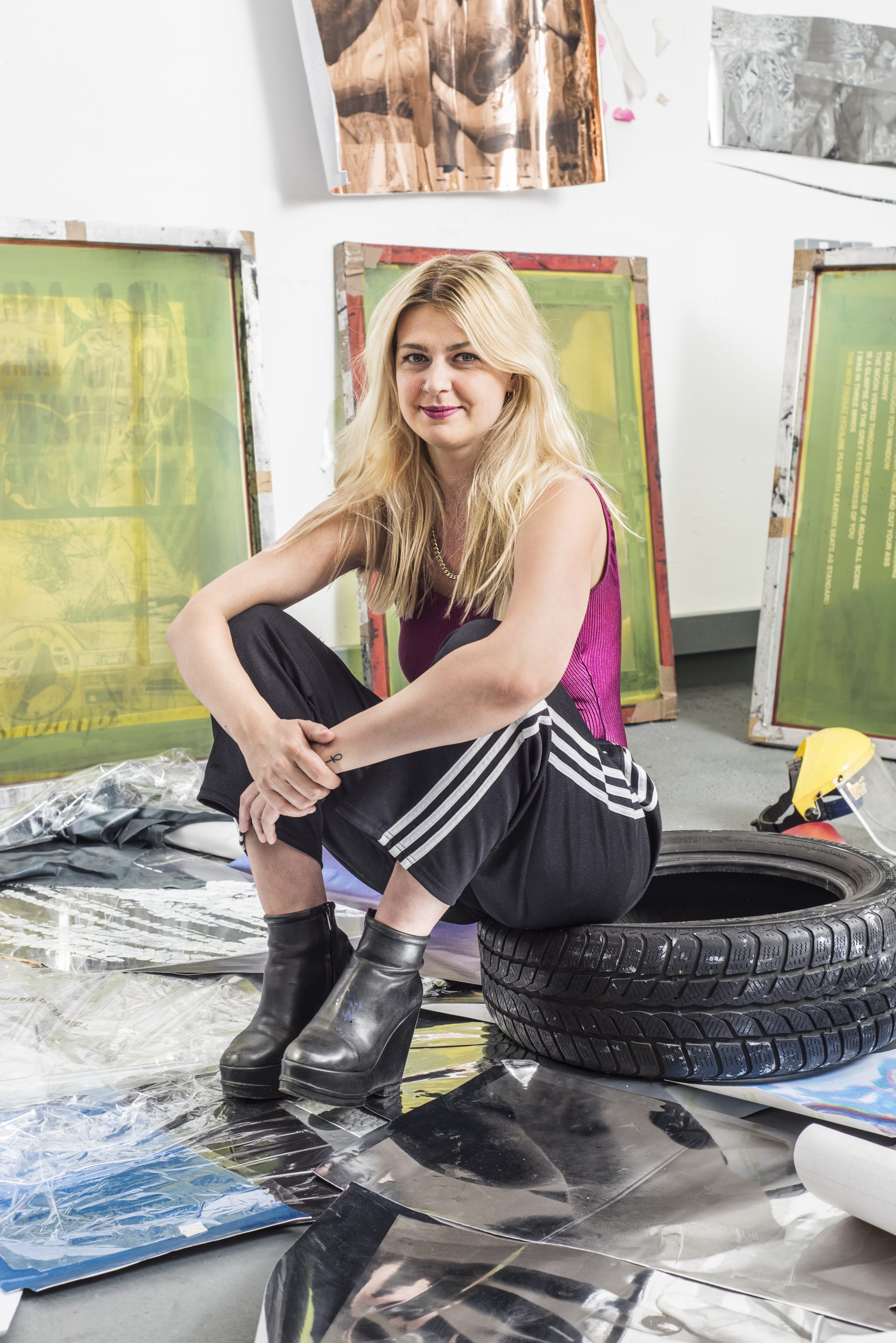 A portrait of Hannah Perry sat on a tyre in the studio