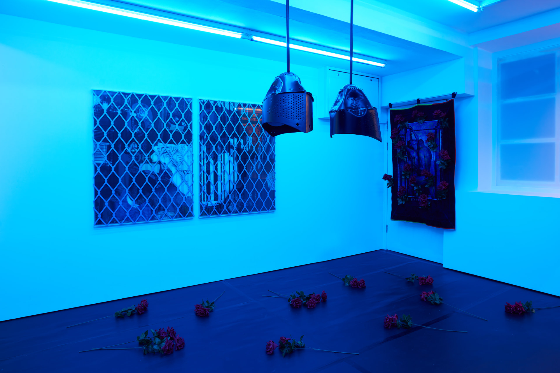 Installation images of Simeon Barclay's exhibition at Workplace in London, artworks, sculpture and video are cast in filtered blue light of a night club
