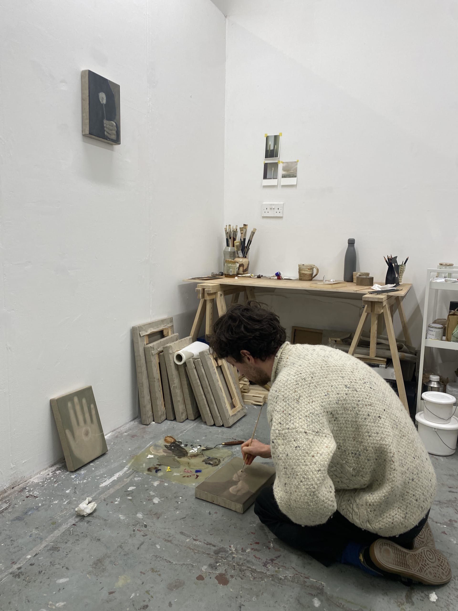 Dylan Williams crouched on the floor of his studio painting a small canvas