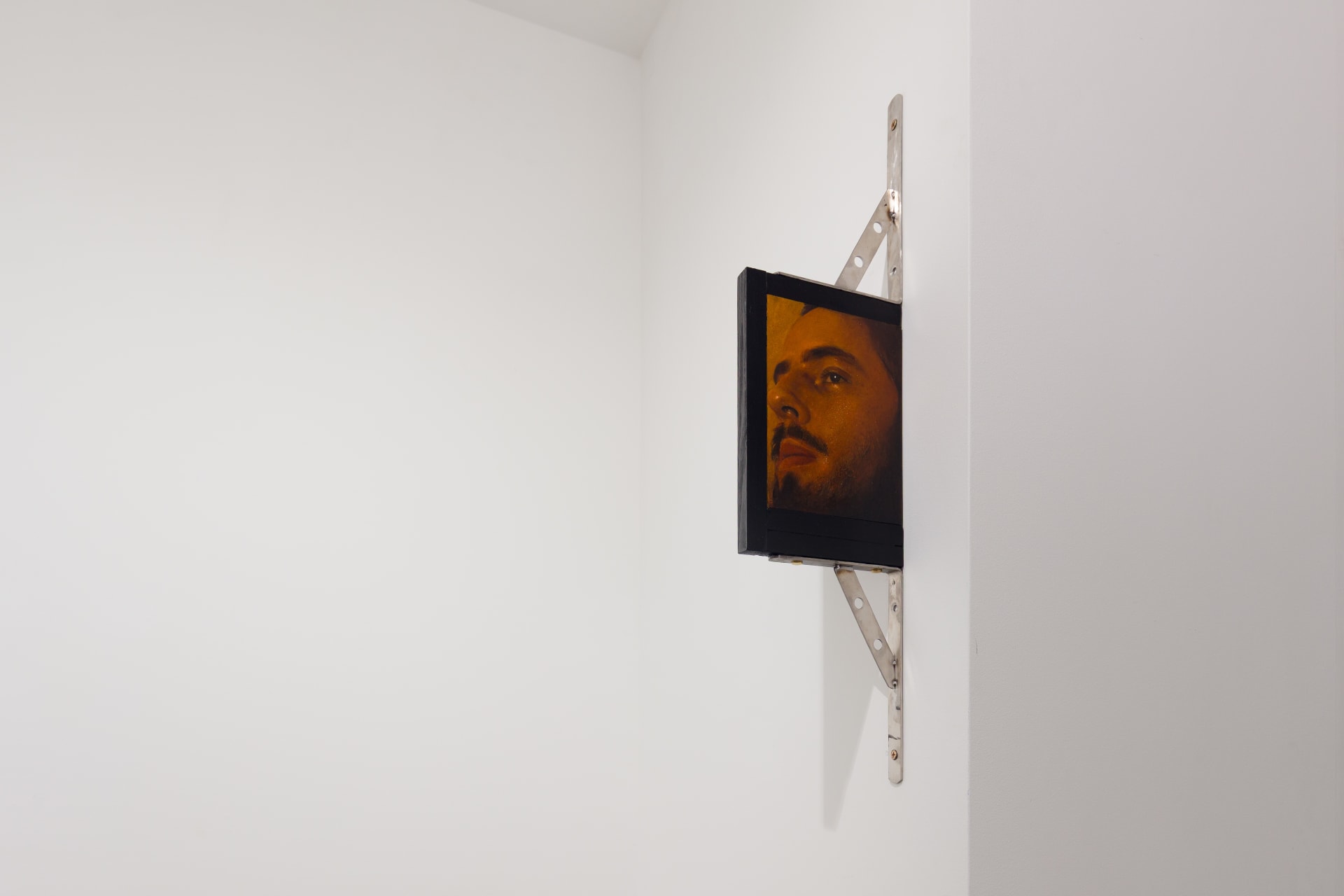 A painting by Ki Yoong of a softly lit young man's face with steel brackets attached to the top and bottom