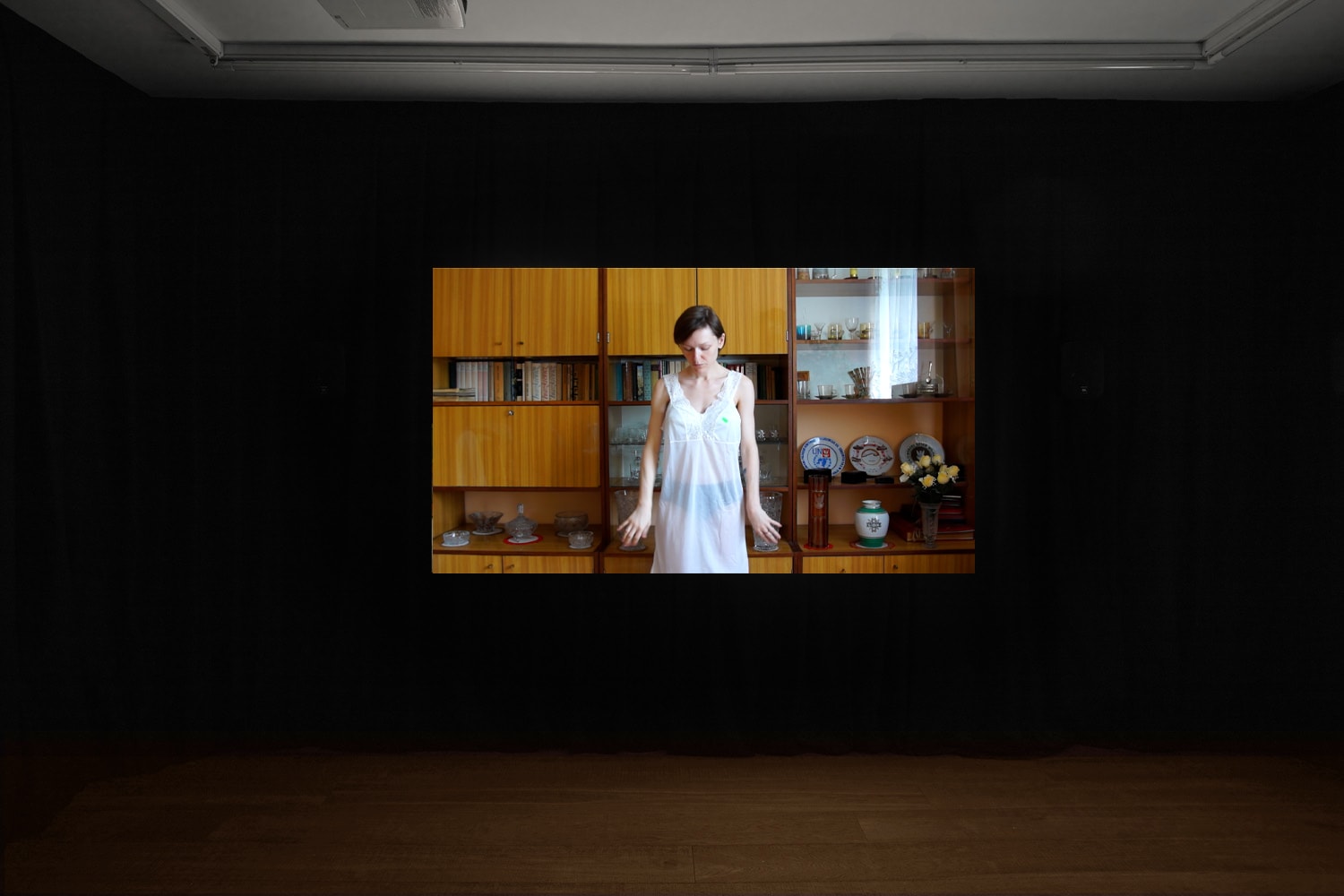 An installation image of Agnieszka Szczotka's film in Workplace's gallery in Margaret Street - Agnieszka wearing her grandmother's white dress in the living room of her grandparents