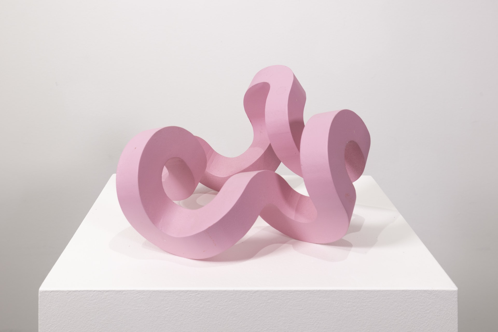 A bright pink sculpture by Jacob Dahlgren of a curved looping structure made from PLA plastic