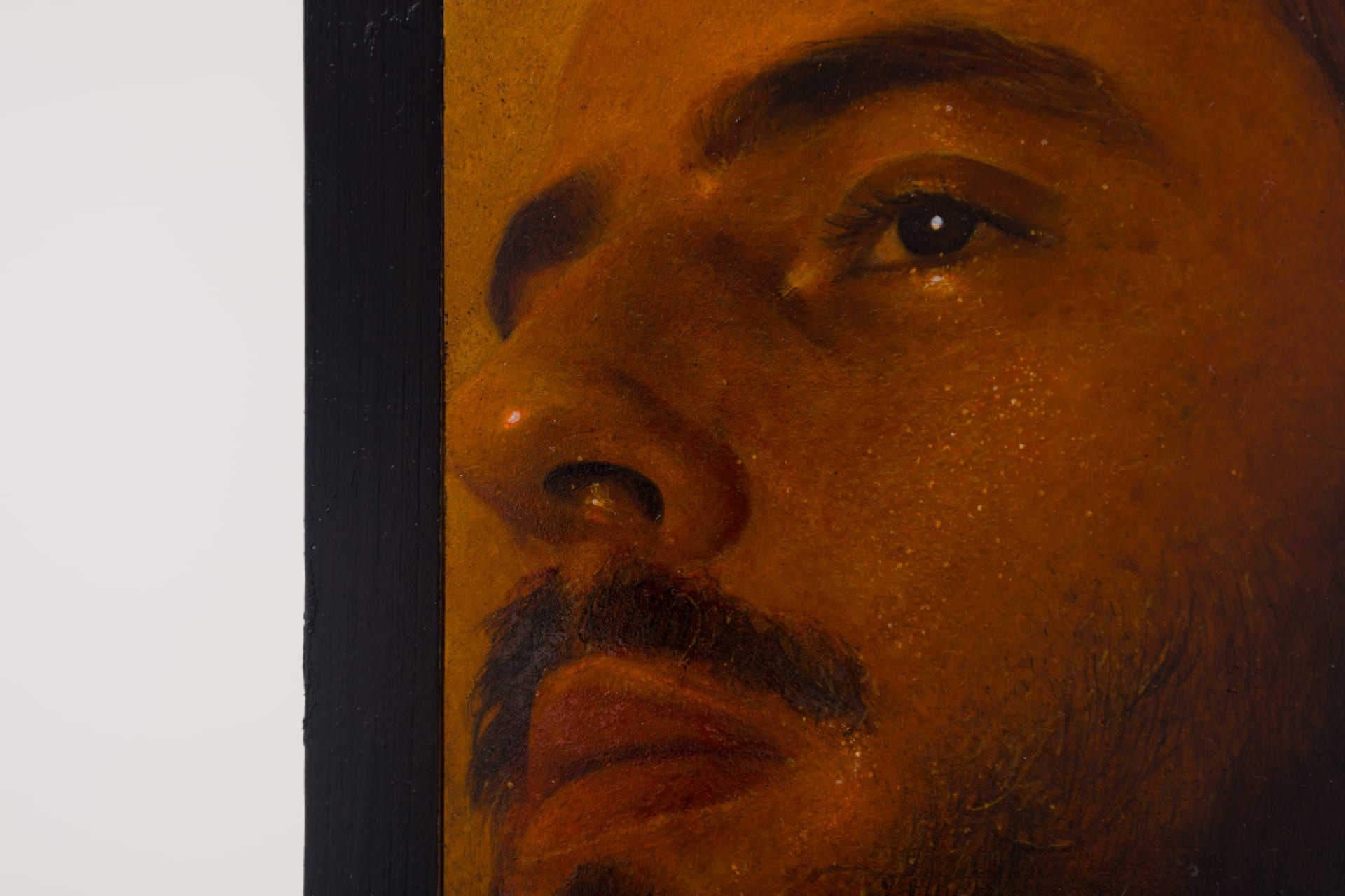 A painting by Ki Yoong of a softly lit young man's face with steel brackets attached to the top and bottom