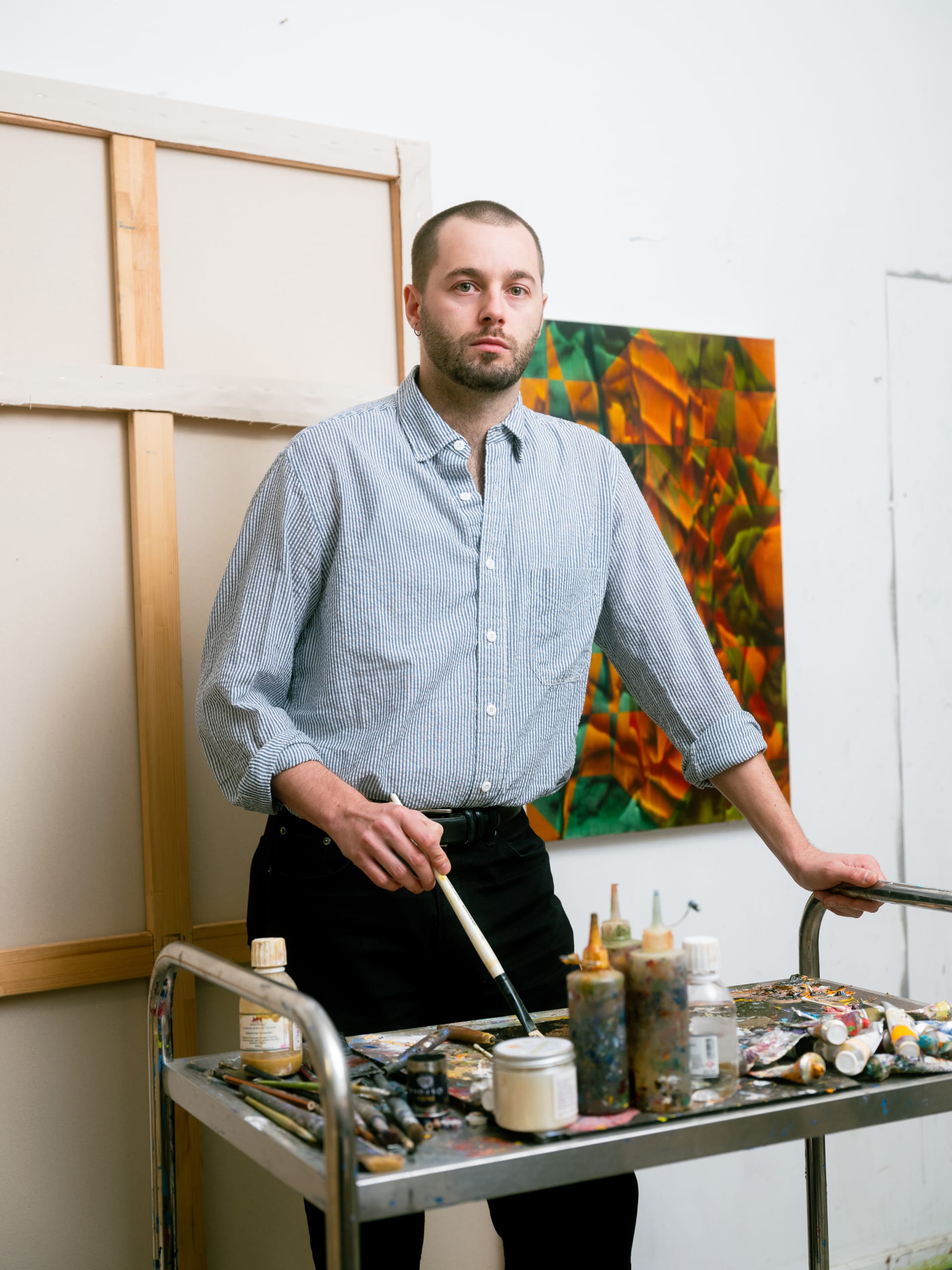 A portrait of Jack Otway holding a paintbrush in his studio