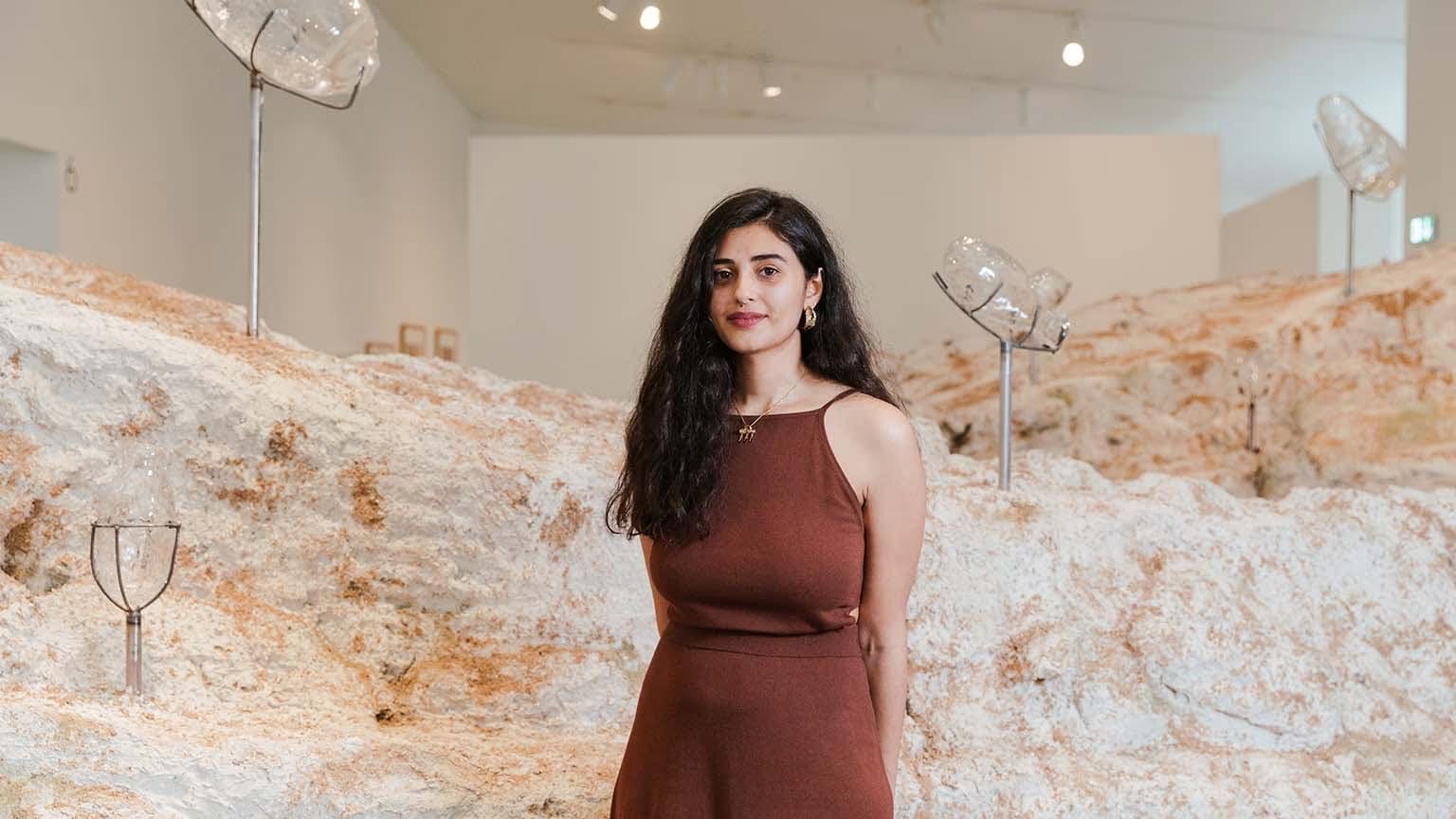 A portrait of Emii Alrai in front of her commission 'A Core of Scar' at The Hepworth Wakefield